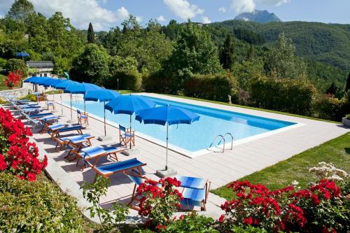 a swimming pool with blue umbrellas and lounge chairs at Casa Vacanze Miravalle in Minucciano