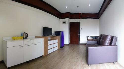 a living room with a couch and a tv in it at Komol Residence Bangkok in Bangkok