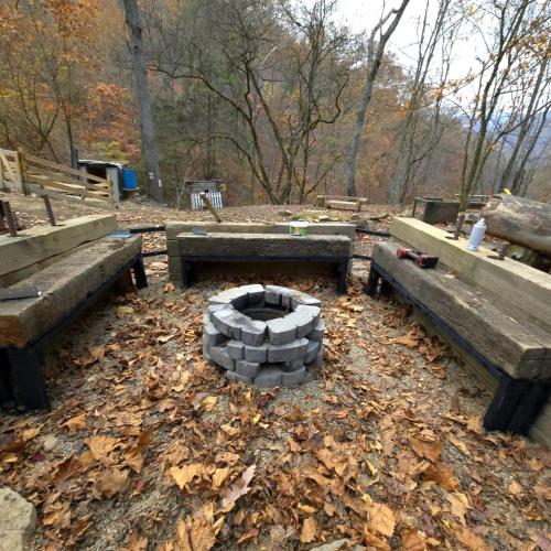 a fire pit in a park with two benches at Remote Mountain A-Frame with BBQ Perfect for Nature Lovers in West Virginia in Malden