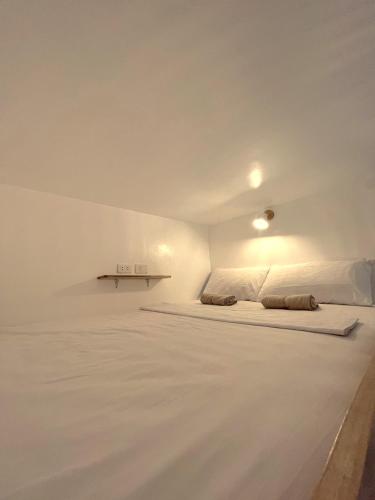 ein weißes Zimmer mit einem Bett und einem Tisch in der Unterkunft Blau Hostel in El Nido