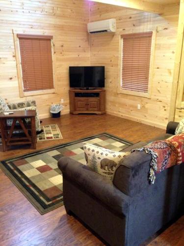a living room with a couch and a flat screen tv at Mammoth Cave Cabin for the Best Holiday in Kentucky in Mammoth Cave