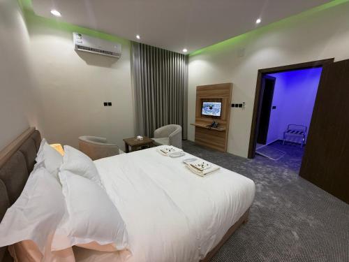 a hotel room with a white bed and a television at شقق دفادف المخدومة in Hail