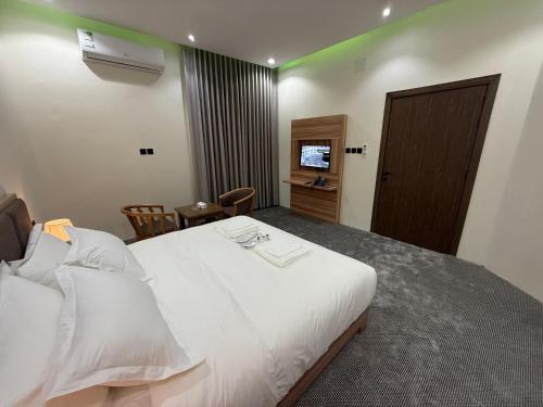 a hotel room with a white bed and a television at شقق دفادف المخدومة in Hail