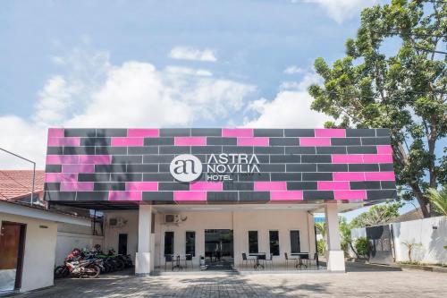 a building with a pink and black sign on it at Capital O 94770 Hotel Astra Novilia in Makassar