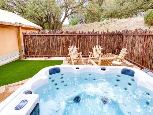 a hot tub in a yard with chairs and a fence at Luxury Cabin, with Hot-Tub Access in Ingram, Texas for Relaxing Weekends Away in Hunt