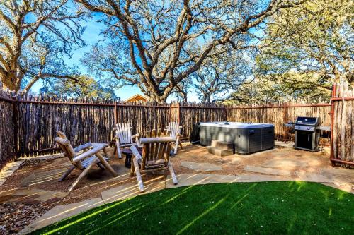 a backyard with two chairs and a grill and a fence at Luxury Cabin, with Hot-Tub Access in Ingram, Texas for Relaxing Weekends Away in Hunt