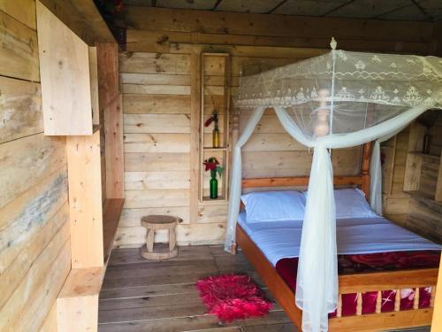 Un dormitorio con una cama en una cabaña de troncos en One love archive, en Chabahinga
