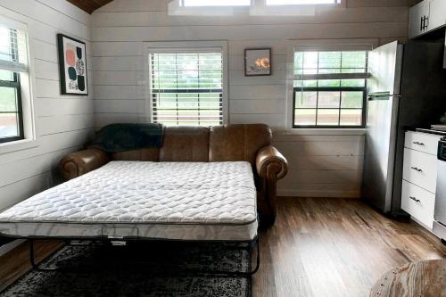 a room with a couch in a kitchen with windows at Entire Three Cabins Property Perfect for Big Groups in Marion, Illinois in Sunset Harbor