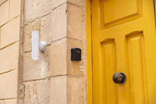 a yellow door on the side of a building at Stay by the Grand Harbour of Valletta in Senglea
