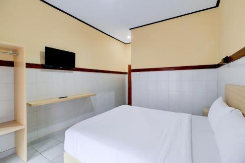 a bedroom with a bed and a flat screen tv at Townhouse Oak @lebak Bene Near Kuta Beach in Legian