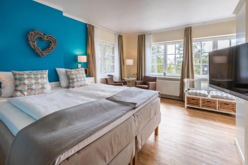 a bedroom with a large bed and a blue wall at Hotel kleine Auszeit - Adults Only in Sankt Peter-Ording