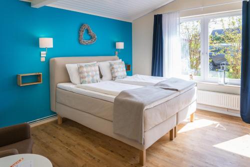 a bedroom with a bed with blue walls and a window at Hotel kleine Auszeit - Adults Only in Sankt Peter-Ording