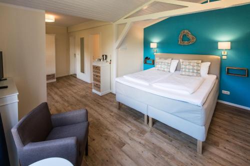 a bedroom with a large bed and a chair at Hotel kleine Auszeit - Adults Only in Sankt Peter-Ording