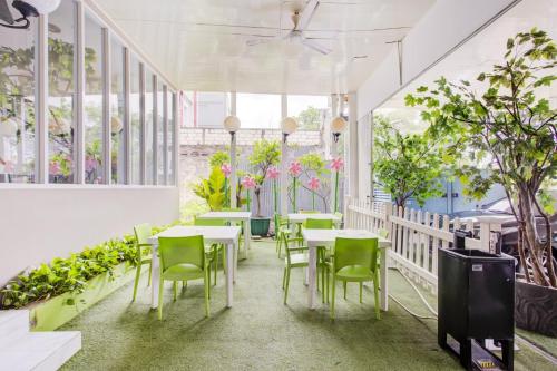 a restaurant with tables and chairs and plants at Capital O 94792 Aleander Hotel in Jakarta