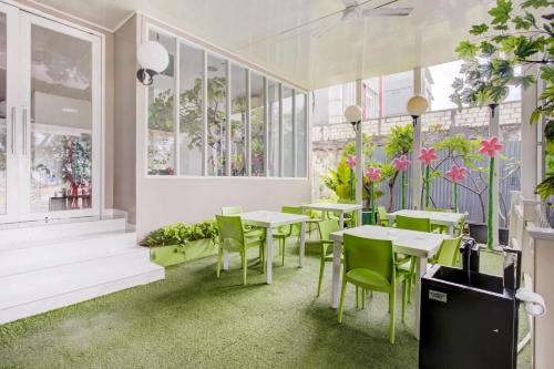 a restaurant with tables and chairs and plants at Capital O 94792 Aleander Hotel in Jakarta