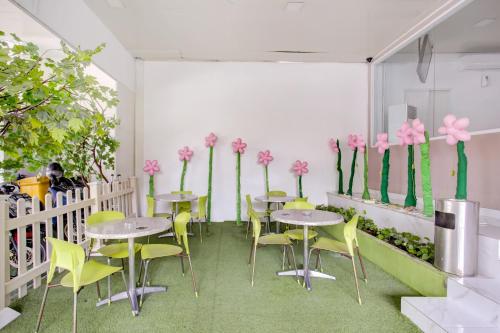 a room with tables and yellow chairs and pink flowers at Capital O 94792 Aleander Hotel in Jakarta