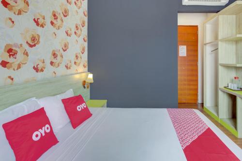 a bedroom with a white bed with red pillows at Capital O 94792 Aleander Hotel in Jakarta