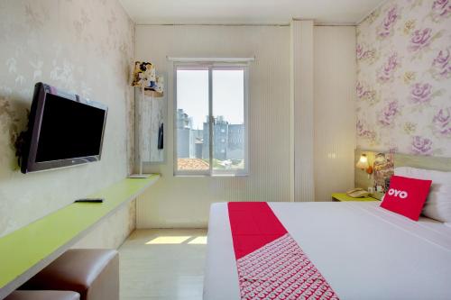 a bedroom with a bed and a tv and a window at Capital O 94792 Aleander Hotel in Jakarta