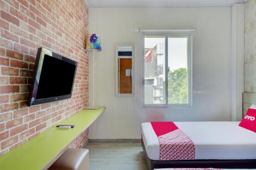 a bedroom with a bed and a tv on a brick wall at Capital O 94792 Aleander Hotel in Jakarta