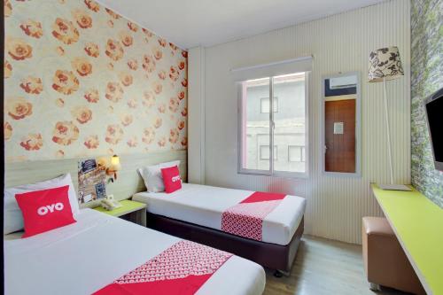 a hotel room with two beds and a window at Capital O 94792 Aleander Hotel in Jakarta
