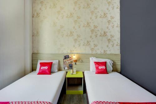 two beds in a small room with red pillows at Capital O 94792 Aleander Hotel in Jakarta