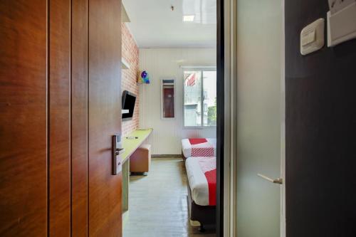 a room with a bedroom with a bed and a desk at Capital O 94792 Aleander Hotel in Jakarta