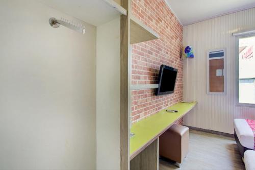 a room with a green desk and a brick wall at Capital O 94792 Aleander Hotel in Jakarta