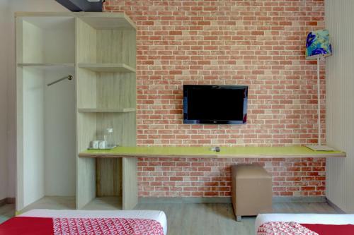 a brick wall with a desk with a tv on it at Capital O 94792 Aleander Hotel in Jakarta