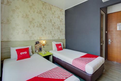 two beds in a room with red and white pillows at Capital O 94792 Aleander Hotel in Jakarta