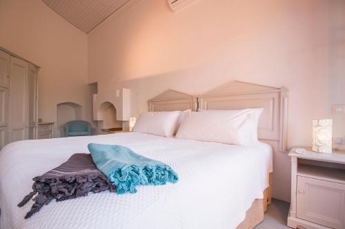 a bedroom with a white bed with a blue blanket on it at The Old Markets in Symi