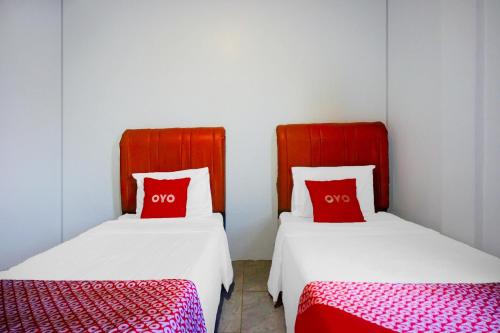 two beds with red pillows in a room at OYO 94787 Hotel Mulana in Banda Aceh