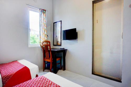a bedroom with a bed and a desk and a window at OYO 94787 Hotel Mulana in Banda Aceh