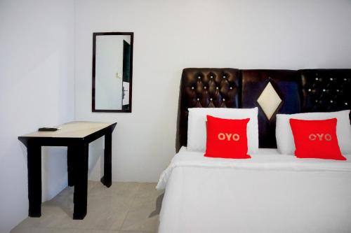 a bedroom with a bed with red pillows and a table at OYO 94787 Hotel Mulana in Banda Aceh