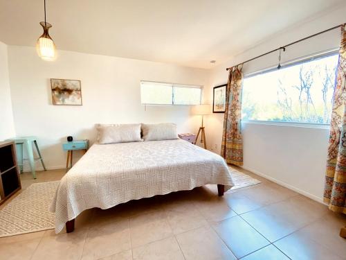 ジョシュア・ツリーにあるBeautiful Vacation Rental with Hot Tub Perfect for Glamping in Joshua Treeのベッドと大きな窓のある寝室