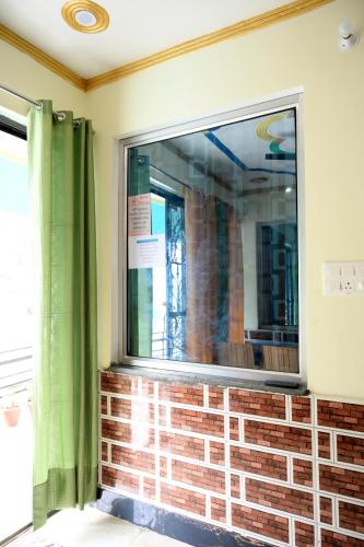 a window with a brick wall and green curtains at maa kalishila home stay in Ukhimath