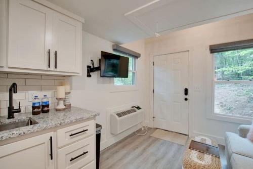 a kitchen with white cabinets and a sink and a window at Colorful Tiny House with Outdoor Sauna and Jacuzzi in Alabama in Grant