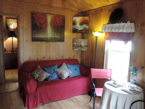 a living room with a red couch and a table at Cozy and Comfortable Cabin Rental Just 15 Minutes from San Antonio, Texas in Kreutzberg