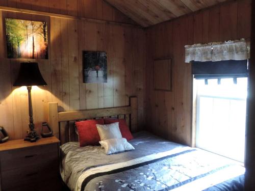a bedroom with a bed and a lamp and a window at Cozy and Comfortable Cabin Rental Just 15 Minutes from San Antonio, Texas in Kreutzberg