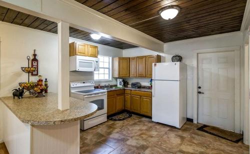 a kitchen with a white refrigerator and wooden cabinets at Fantastic Log Cabin Rental for a Fun-Filled Family Vacation in Texas in Nacogdoches