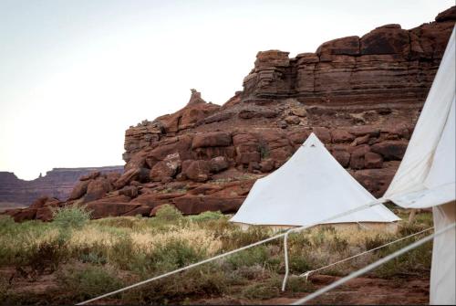 Allen Memorial Hospital HeliportにあるIntimate Glamping Tent near Arches National Park for a Memorable Couples Escape in Moab, Utahの岩山前白いテント