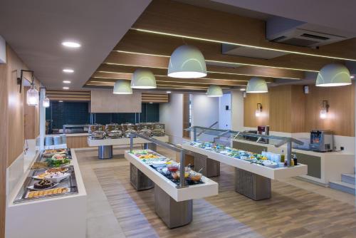 a cafeteria with a buffet line with food on display at Stella Village Seaside Hotel in Hersonissos