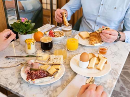 a table with plates of breakfast food on it at Mercure Lyon Centre Château Perrache in Lyon