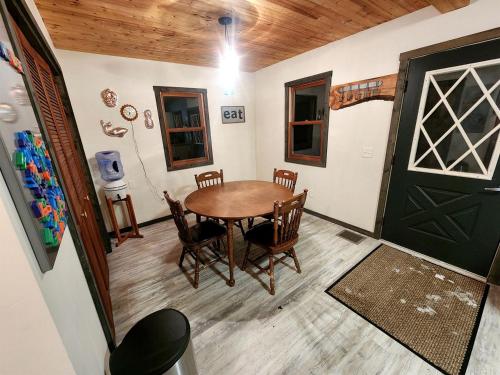 une salle à manger avec une table, des chaises et une porte dans l'établissement Secluded Luxury Cabin with Hot Tub on 10 Private Acres near Trails in Reed City, Michigan, à Idlewild