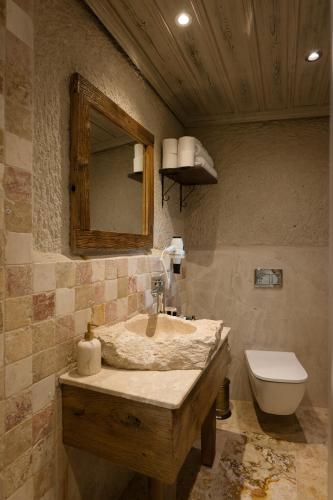a bathroom with a sink and a toilet and a mirror at Cappadocia Cave Suites Adult Only in Goreme