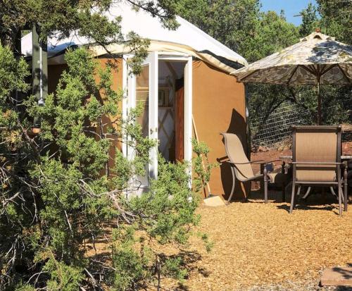 a house with an umbrella and a table and chairs at Charming Yurt in the Cibola National Forest near Albuquerque, New Mexico in Tijeras