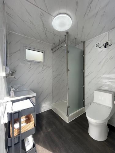 a bathroom with a shower and a toilet and a sink at GLAMFOREST Okinawa 名護 in Nago