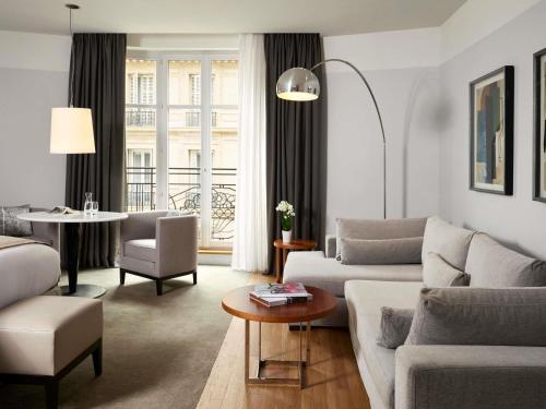 a living room with a couch and a table at Sofitel Paris Arc De Triomphe in Paris