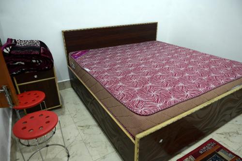 a bed with a purple mattress and a red stool at maa kalishila home stay in Ukhimath