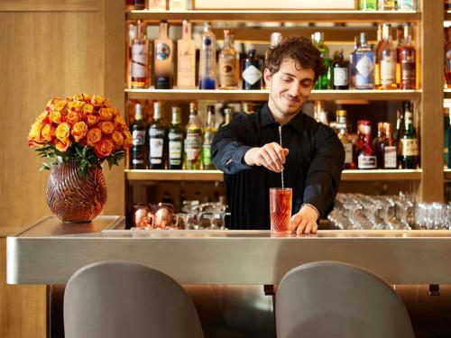 a man standing at a bar with a drink at Sofitel Paris Arc De Triomphe in Paris