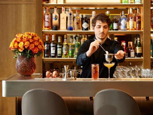 a man sitting at a bar making a drink at Sofitel Paris Arc De Triomphe in Paris